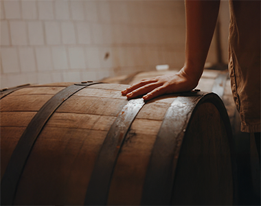 Main d’un homme touchant un baril de bière artisanale.