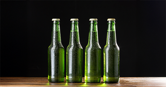 Quatre bouteilles de bière sans étiquette posées devant un fond noir.